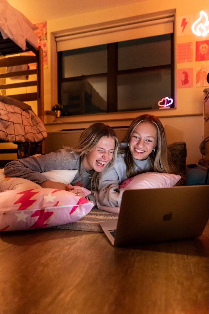 Students in residence hall looking at a computer and laughing