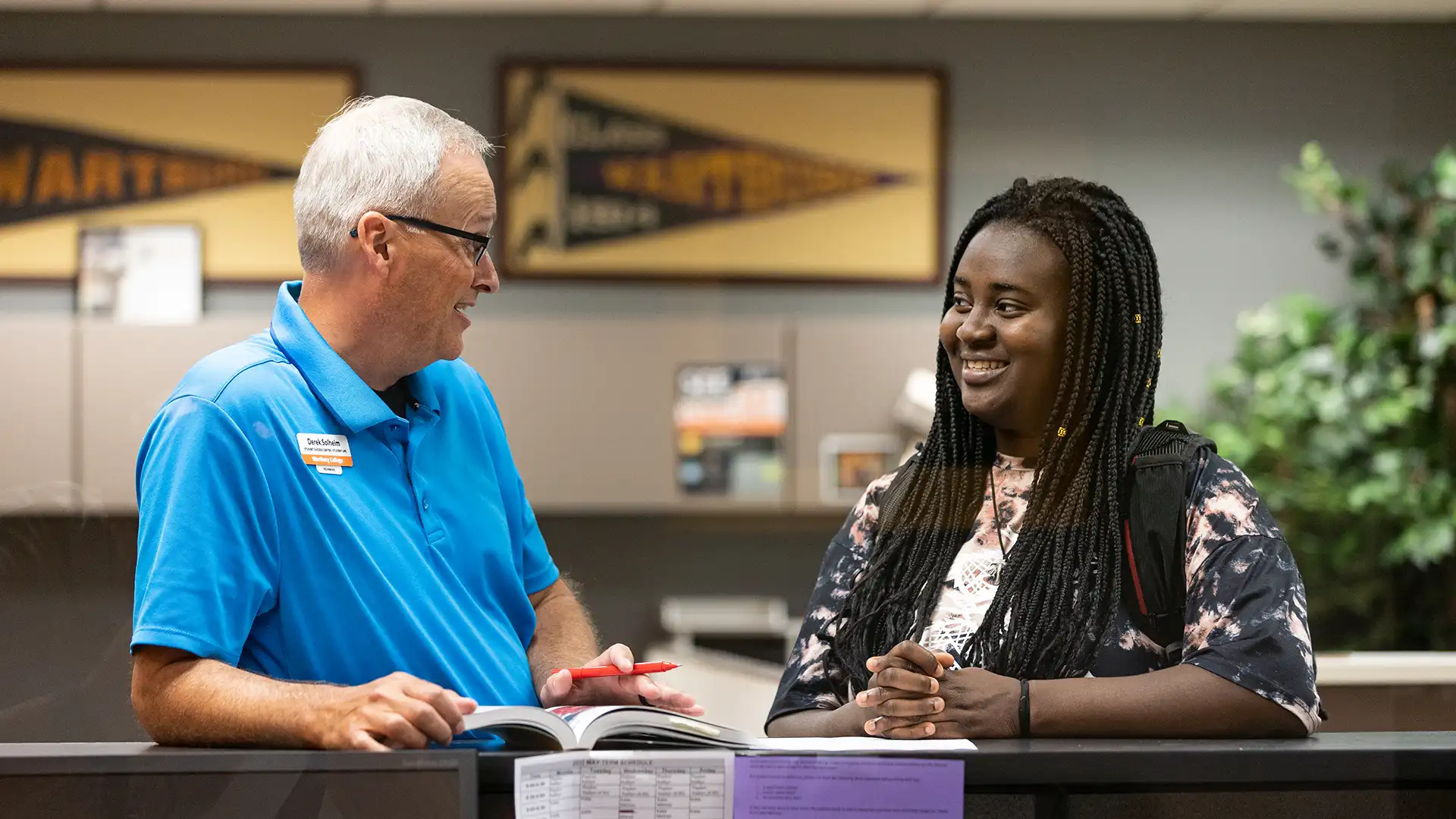 Derek Solheim works with a student while standing at the counter